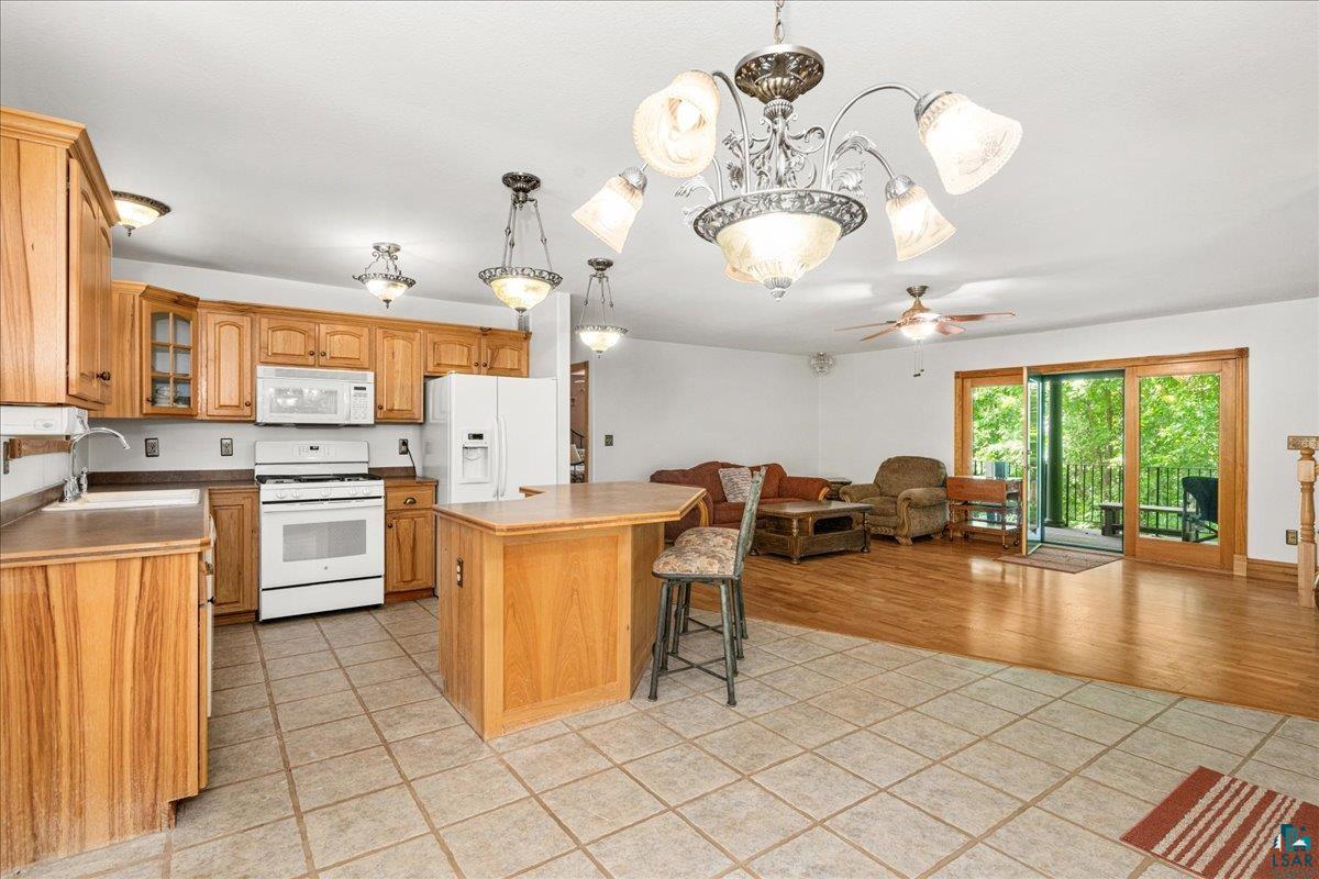 3799 South Lake Road Moose Lake, MN 55767 - Photo 10 of 35 Open-concept kitchen featuring wood cabinetry, white appliances, and a central island with bar seating