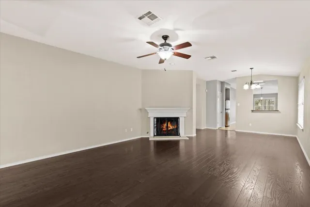 a view of an empty room with a kitchen and wooden floor
