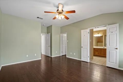 an empty room with wooden floor and a ceiling fan