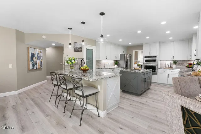 a kitchen with granite countertop a sink stainless steel appliances and white cabinets
