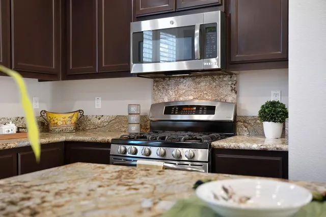 a kitchen with stainless steel appliances kitchen island granite countertop a stove and a microwave