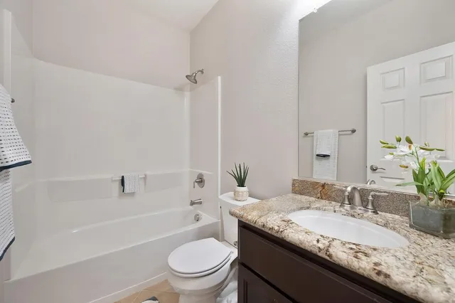 a bathroom with a granite countertop sink a toilet and bathtub