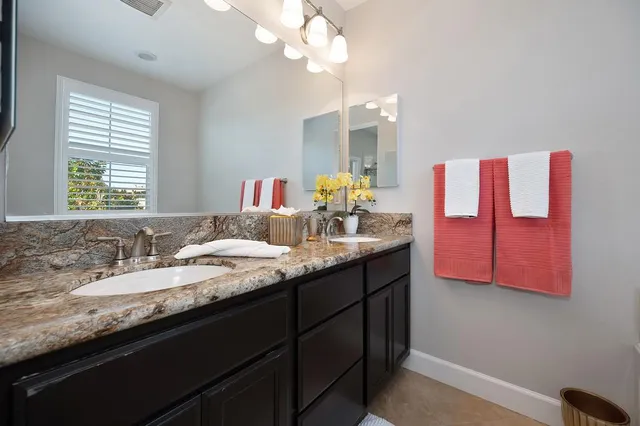 a bathroom with a granite countertop sink a large mirror and a window