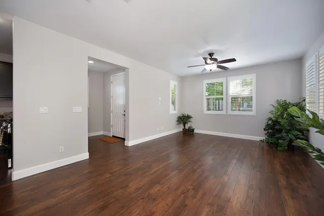 a view of an empty room with wooden floor and a window