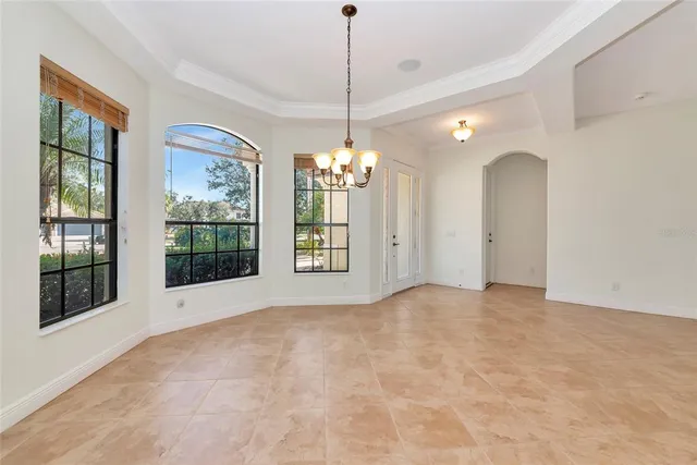 an empty space with chandelier fan and windows