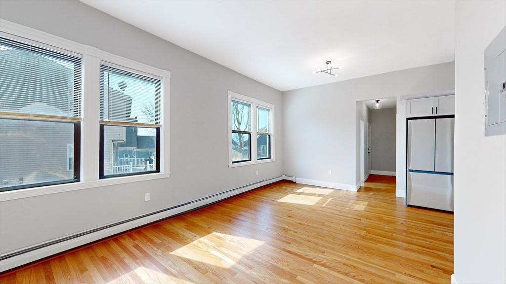 181 Highland Street, Unit 1 Boston, MA 02119 - Photo 4 of 11 a view of an empty room with window and wooden floor