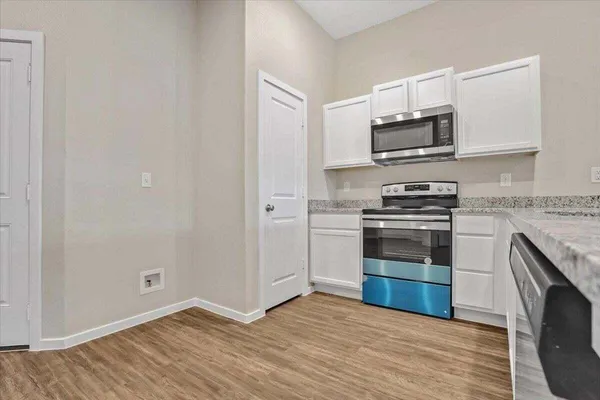 a kitchen with stainless steel appliances white cabinets and a stove top oven