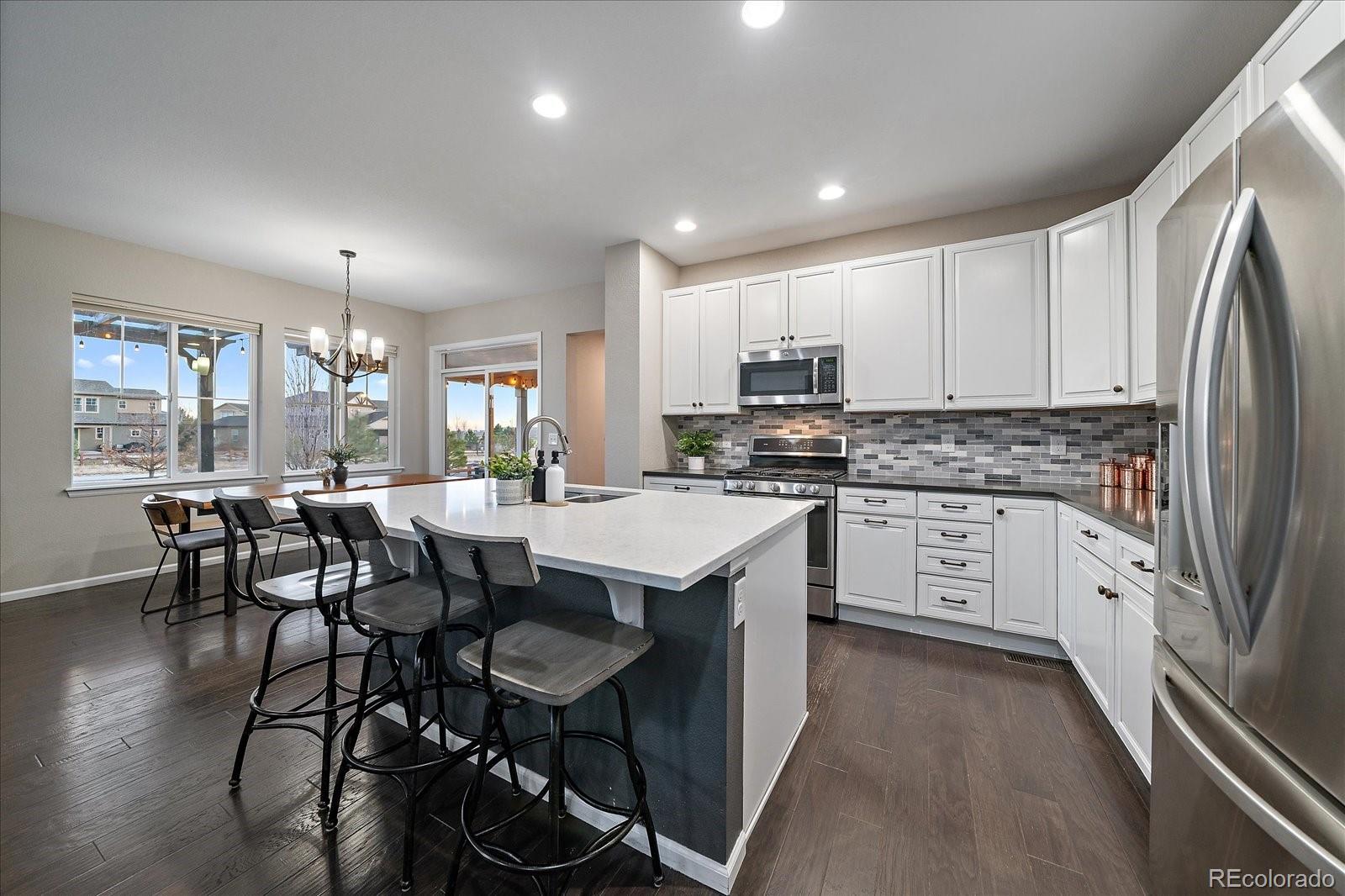 9382 Noble Way Arvada, CO 80007 - Photo 8 of 42 a kitchen with kitchen island granite countertop wooden cabinets and stainless steel appliances