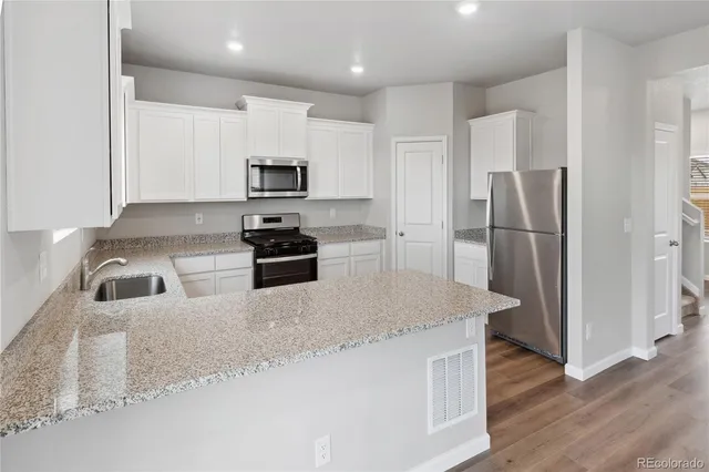 a kitchen with stainless steel appliances granite countertop a refrigerator a stove a sink and a granite counter tops