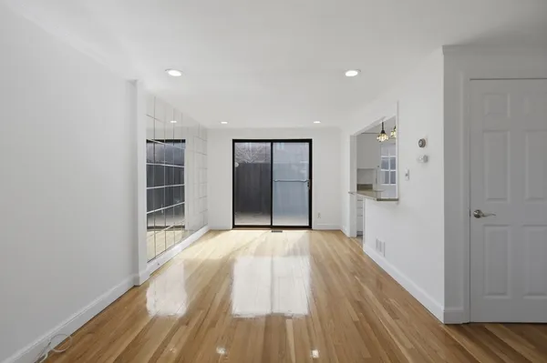 a view of an empty room with wooden floor and a bathroom