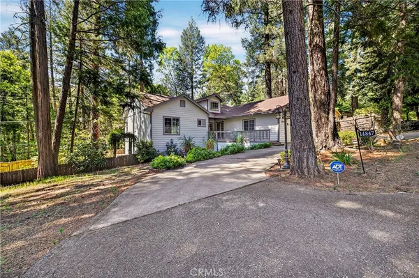 a front view of a house with a garden and tree