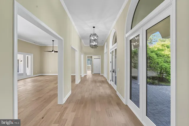 a view of a hallway with wooden floor and chandelier