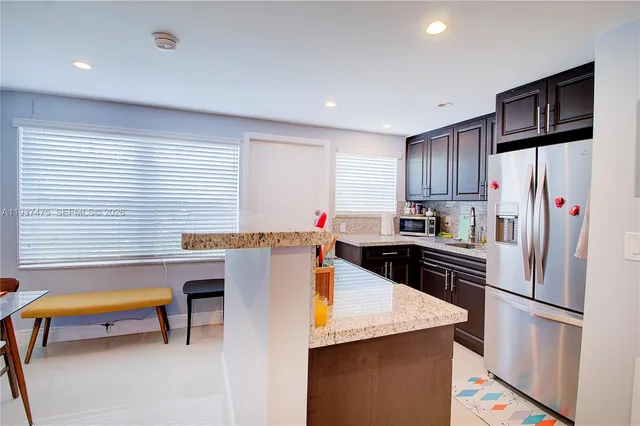 a kitchen with granite countertop a refrigerator a stove a sink dishwasher and wooden cabinets with wooden floor