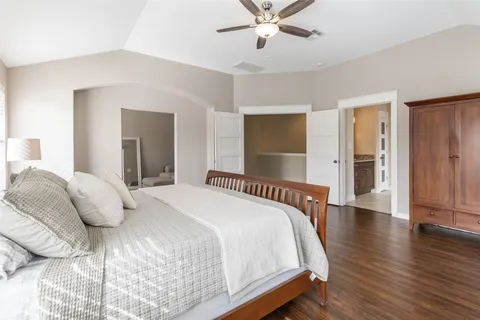 a bedroom with a large bed and wooden floor
