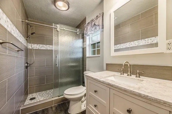 a bathroom with a shower sink vanity mirror and toilet