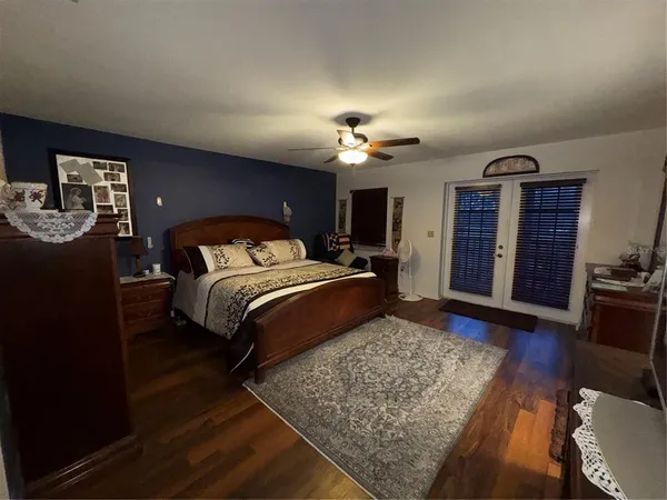 a bedroom with a large bed dresser and wooden floor