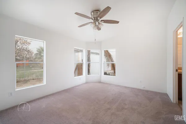 an empty room with windows and fan
