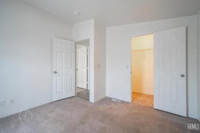 a view of an empty room with closet and a window
