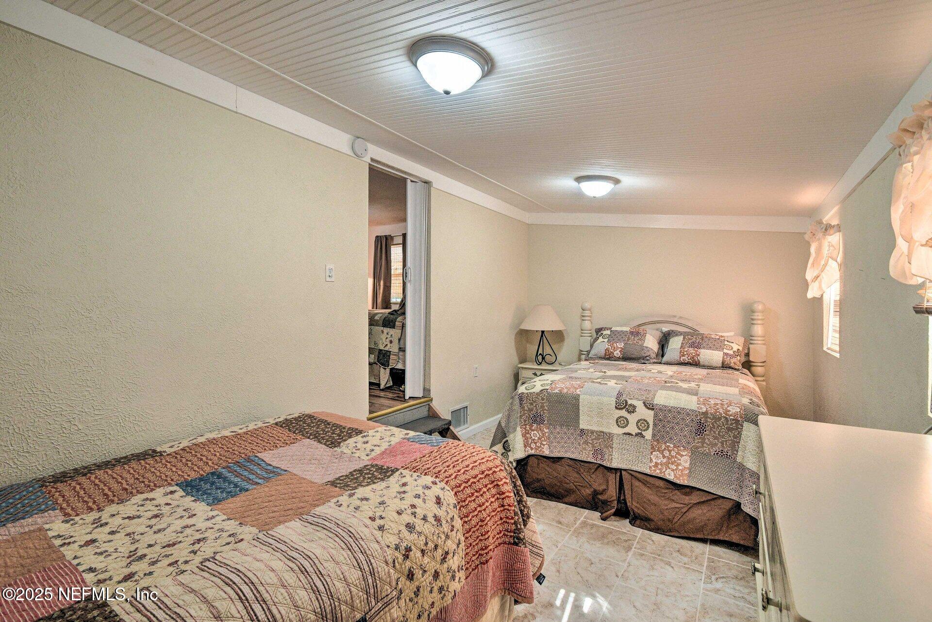 118 Riverside Avenue Satsuma, FL 32189 - Photo 16 of 27 a bedroom with a bed and a chandelier