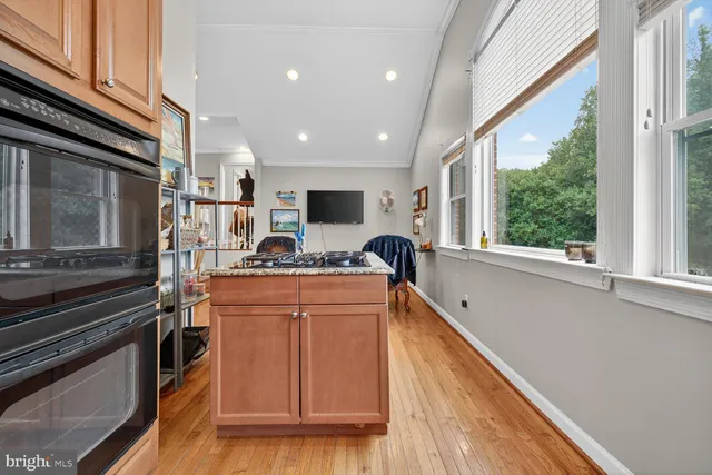 a kitchen with stainless steel appliances granite countertop a refrigerator a stove top oven and a sink with wooden floor