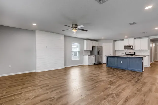 a view of a kitchen with a stove cabinets a ceiling fan and wooden floor