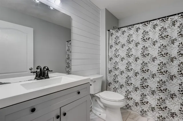 a bathroom with a sink a toilet and shower curtain