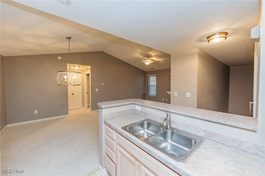 28360 Center Ridge Road, Unit 2210 Westlake, OH 44145 - Photo 22 of 45 Kitchen with hanging light fixtures, sink, vaulted ceiling, light colored carpet, and ceiling fan with notable chandelier