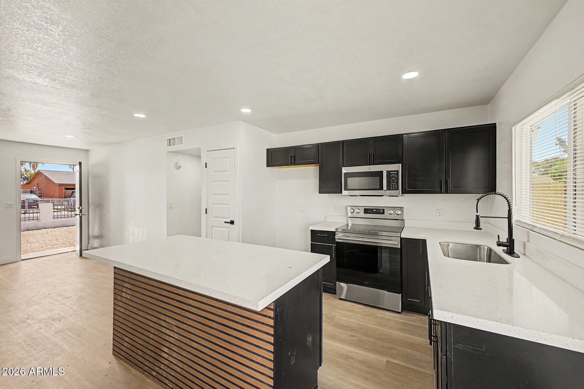 7214 West Flower Street Phoenix, AZ 85033 - Photo 12 of 29 a kitchen with stainless steel appliances a stove top oven a sink a refrigerator white cabinets and wooden floor