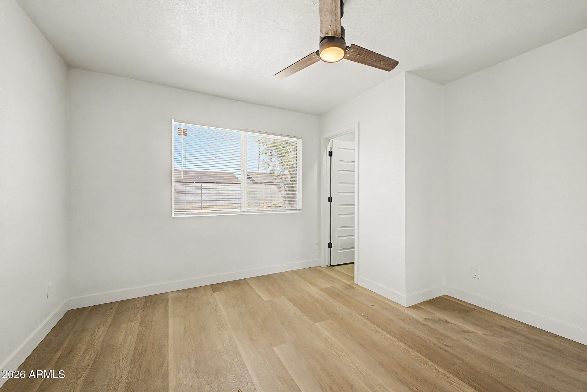 7214 West Flower Street Phoenix, AZ 85033 - Photo 13 of 29 an empty room with wooden floor chandelier fan and windows