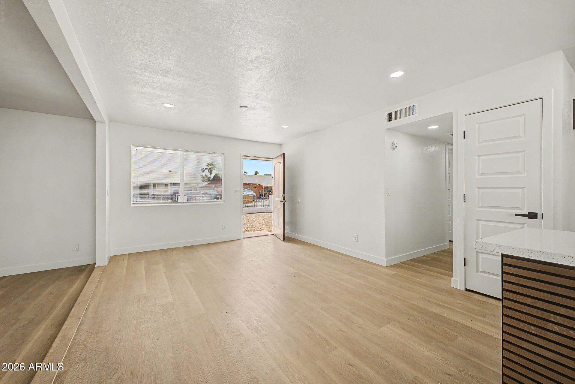 7214 West Flower Street Phoenix, AZ 85033 - Photo 4 of 29 an empty room with wooden floor cabinet and windows