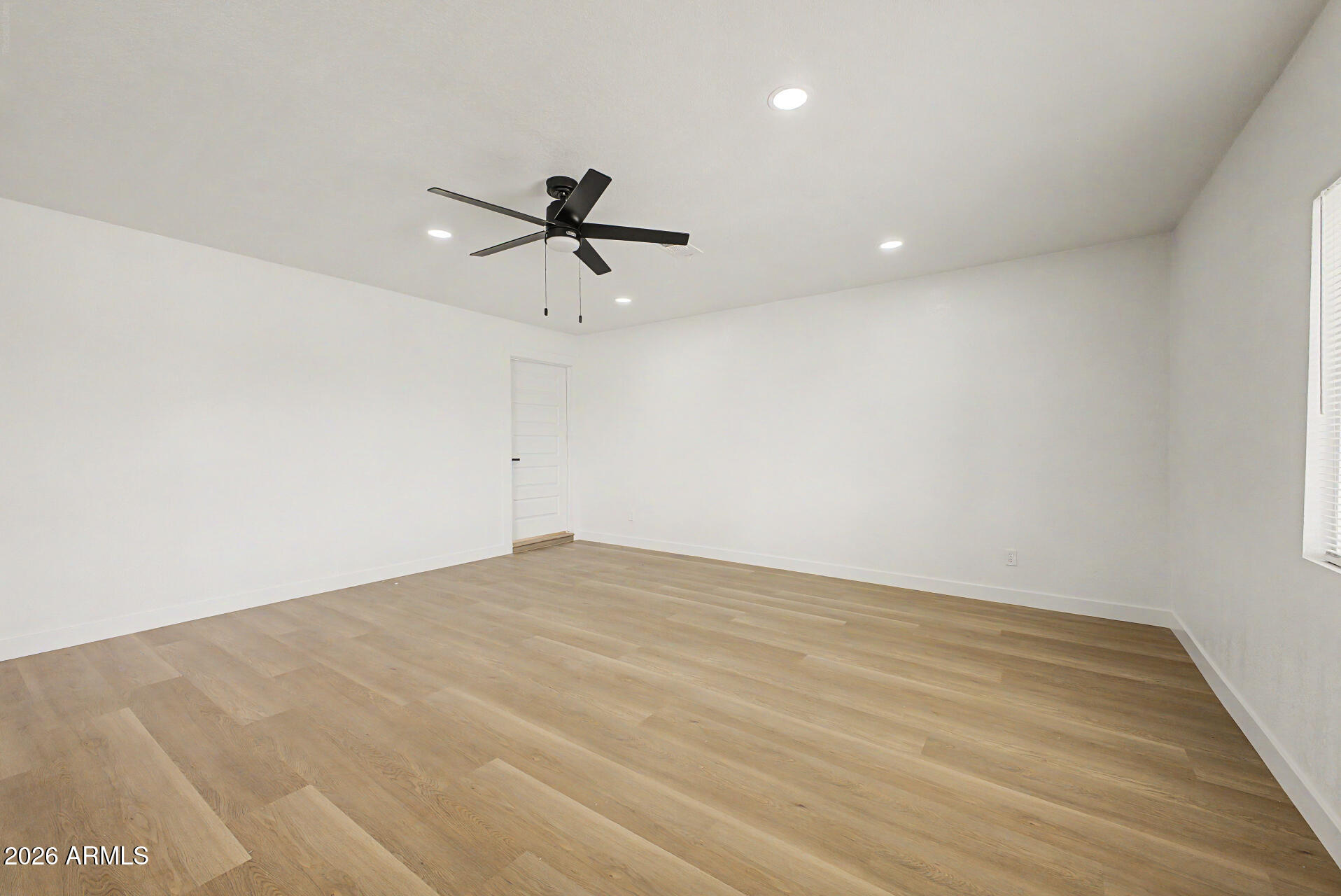 7214 West Flower Street Phoenix, AZ 85033 - Photo 8 of 29 a view of a big room with wooden floor a ceiling fan and a window