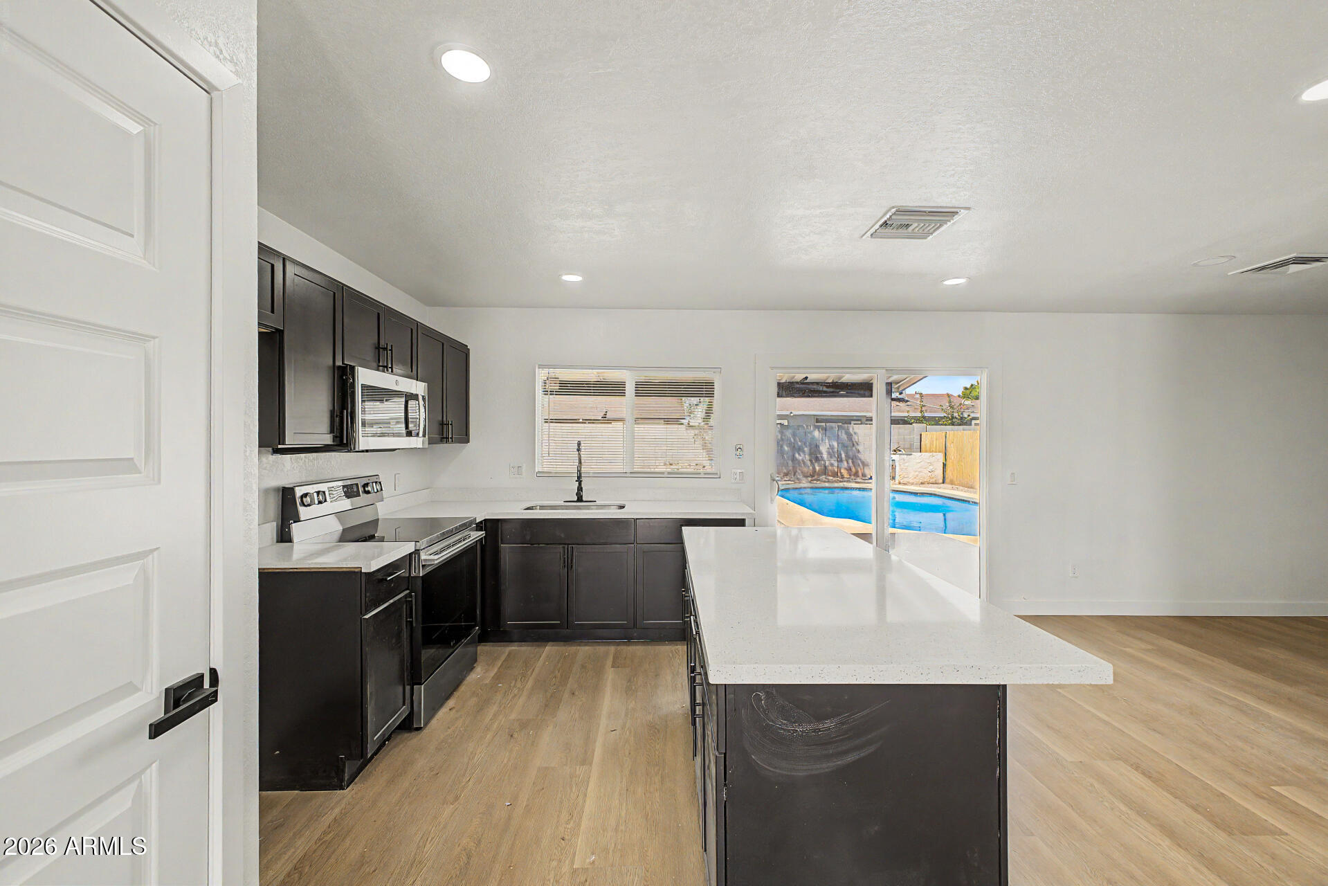 7214 West Flower Street Phoenix, AZ 85033 - Photo 9 of 29 a kitchen with stainless steel appliances a sink stove and wooden floor