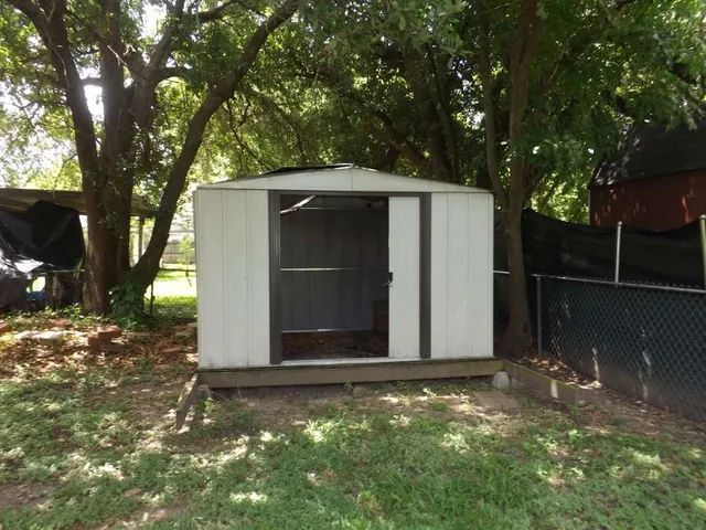 a view of backyard with potted plants and large trees