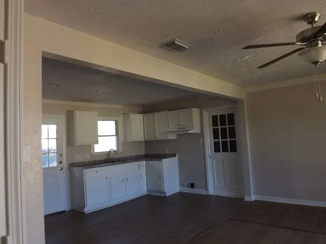 a kitchen with granite countertop white cabinets and window
