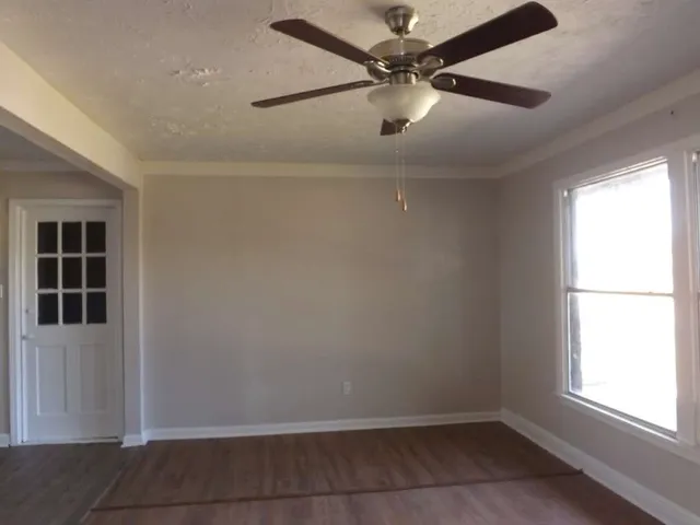 an empty room with windows and fan