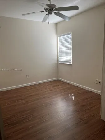 an empty room with wooden floor closet and windows