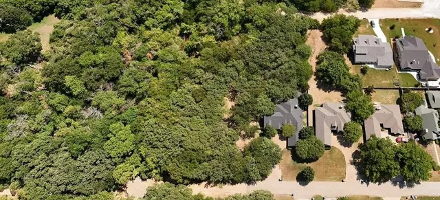 an aerial view of residential house with outdoor space and trees all around