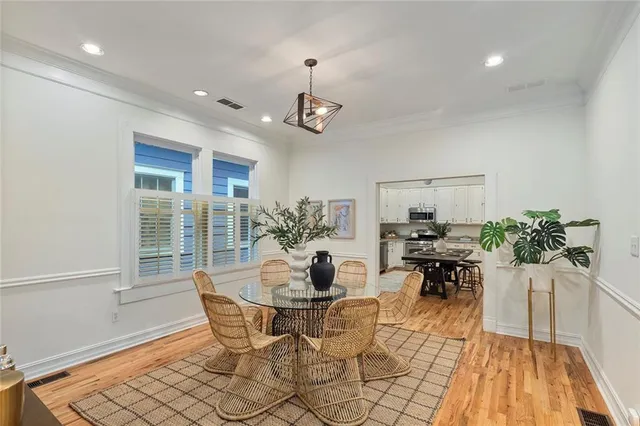 a dining room with wooden floor a chandelier a glass table and chairs