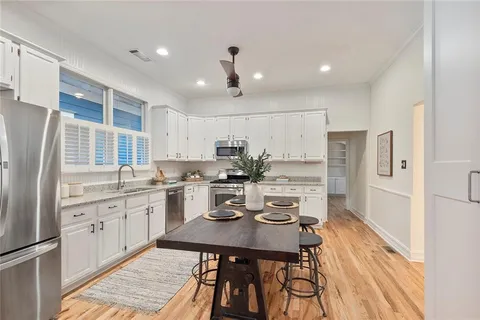 a kitchen with stainless steel appliances kitchen island granite countertop a refrigerator a sink a stove a dining table and chairs