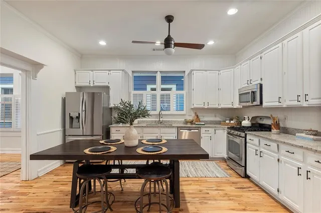 a kitchen with stainless steel appliances granite countertop a dining table chairs stove refrigerator and cabinets