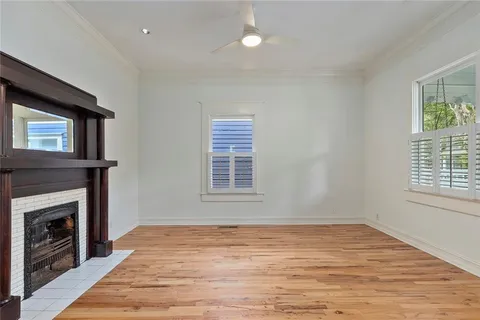 a view of an empty room with wooden floor fireplace and a window