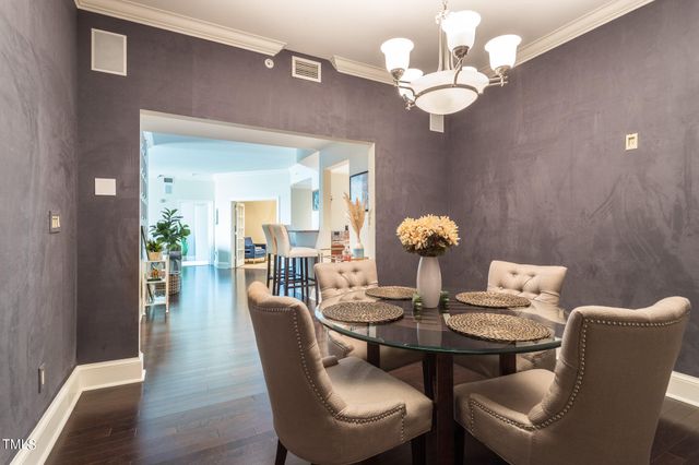 a dining room with wooden floor a chandelier a wooden table and chairs