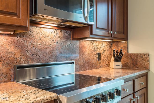 a view of kitchen with granite countertop stove top oven and cabinets