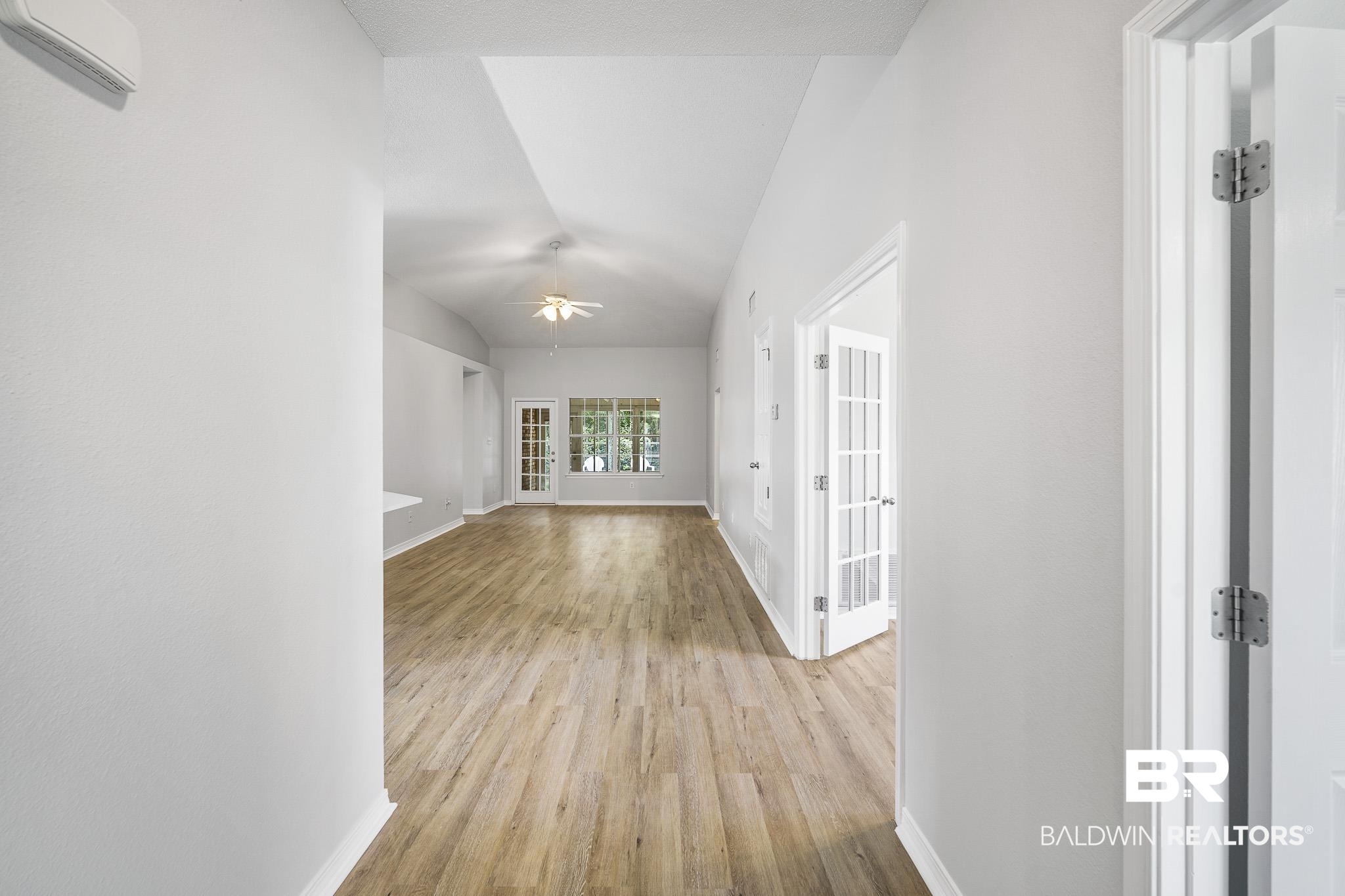 9814 Woolrich Avenue Fairhope, AL 36532 - Photo 11 of 29 Hallway featuring lofted ceiling, french doors, light wood-type flooring, and a wall mounted AC