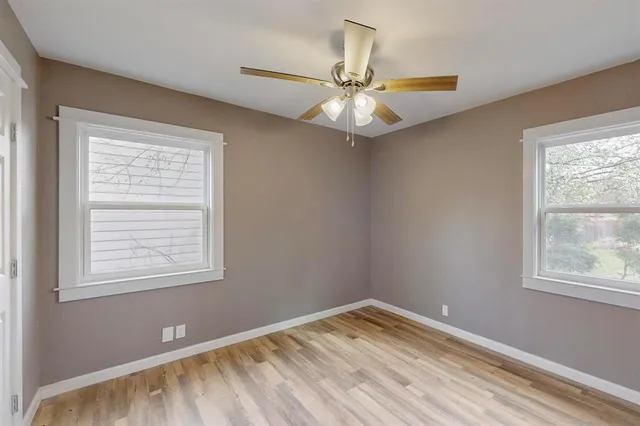 an empty room with windows and fan