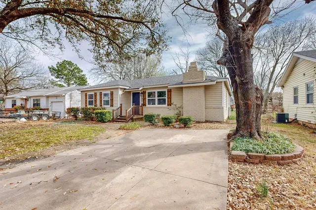 a front view of a house with garden and trees