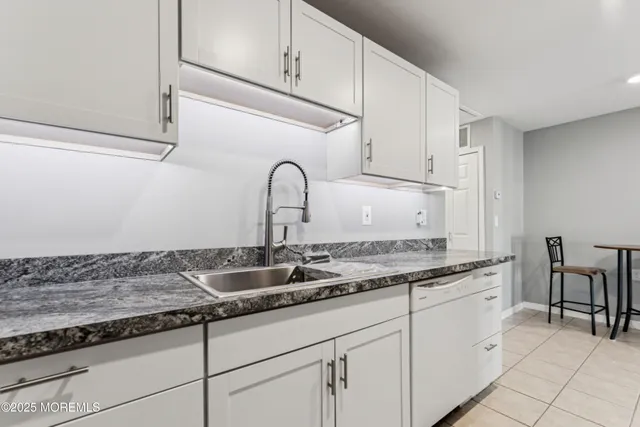 a kitchen with granite countertop white cabinets and sink