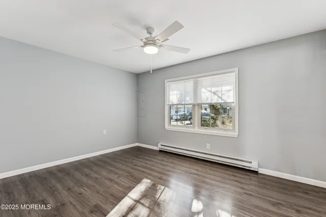 an empty room with wooden floor fan and windows