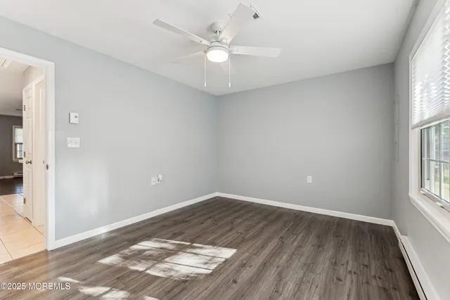 an empty room with windows and ceiling fan