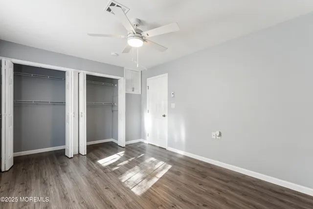 an empty room with wooden floor and ceiling fan